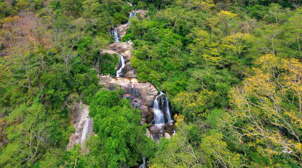 Litet vattenfall som leder ner till en bäck i Nui Chua National Park, Quang Nam, Vietnam